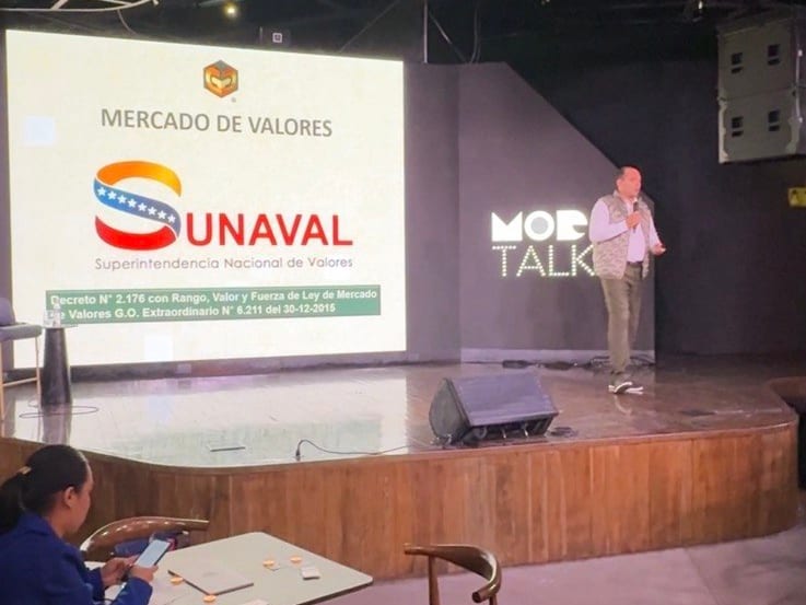 Gibrán González en el escenario de MoDo Caracas, junto a una lámina sobre el mercado de valores